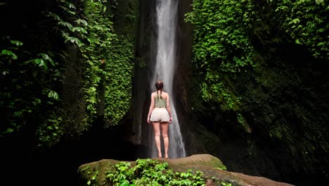 young woman stands mesmerized by the cascading waterfall before her