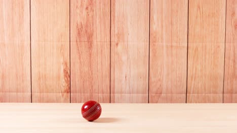 a cricket ball bounces on a wooden floor