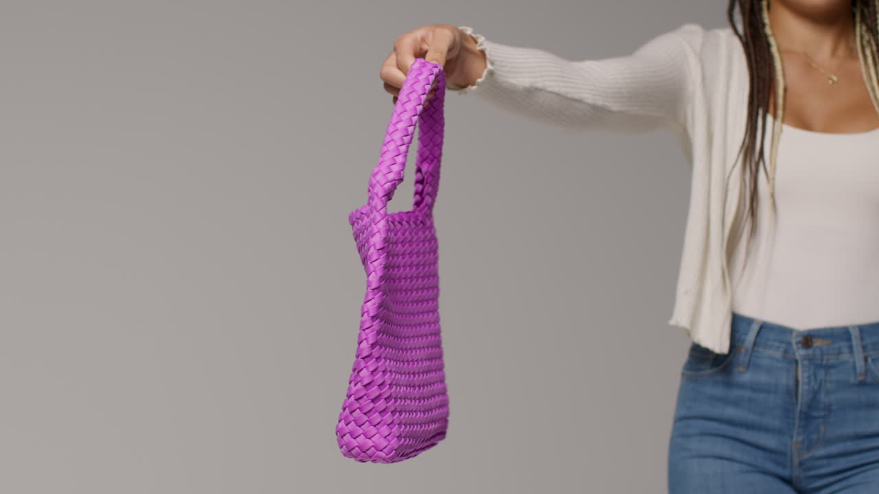 여성 소셜 미디어 인플루언서가 보라색 패션 가방을 들고 사용자 생성 콘텐츠를 제작하는 클로즈업