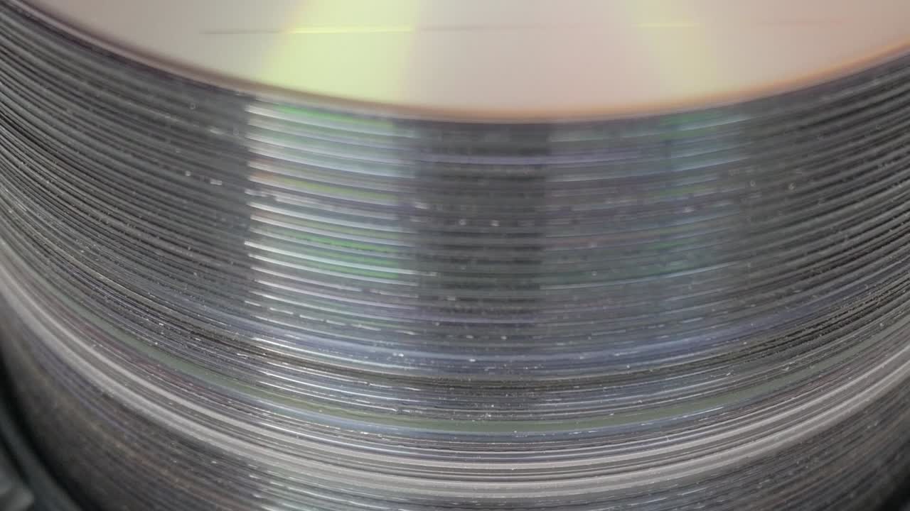Close-up of stacked DVDs showing reflective rainbow colors on surface