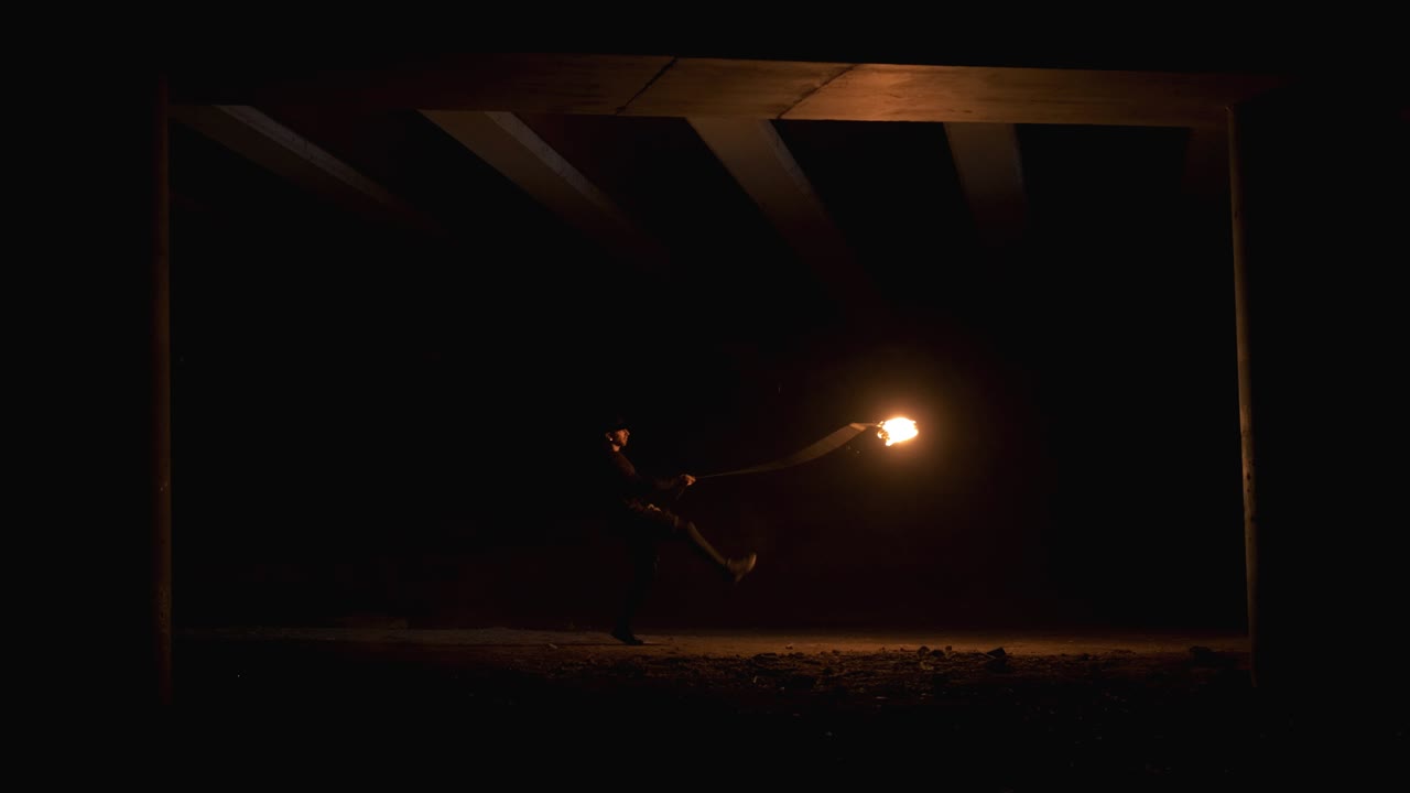 el tipo patea una cuerda con una llama al final. espectáculo de fuego. actuación nocturna. cámara lenta