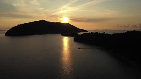 golden sunset over silhouetted islands and ocean with pier