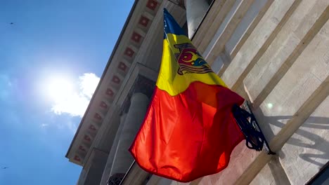 bandera moldava en el asta de la fachada contra la luz solar brillante, ángulo bajo