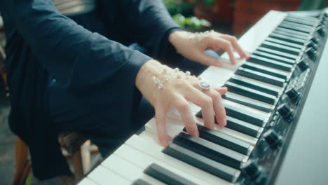 jeweled hands of female musician playing keyboard in orangery