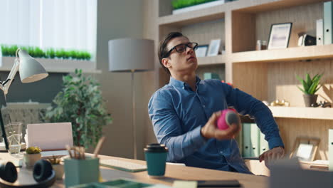 thoughtful man watching computer monitor at office table. creator tossing ball