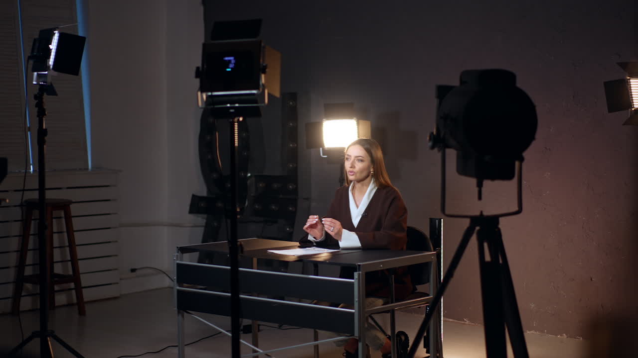 Beautiful Caucasian woman sits at desk talking to camera. Soffits illuminate the lady recording video for blog