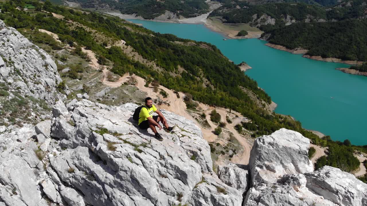 turista sentado en la cima de la montaña admirando la belleza del lago bovilla