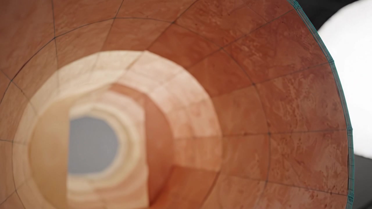 Vista detallada de una escultura de arte moderno que muestra patrones y colores intrincados con una perspectiva evolutiva en un entorno de estudio minimalista