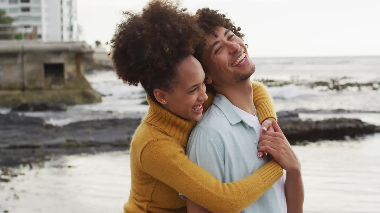 Close up of african american couple embracing each other on the rocks near the sea