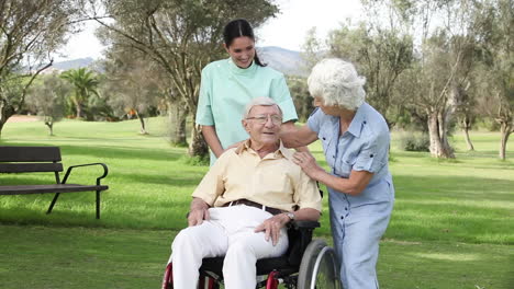 woman and nurse talking to man in wheelchair