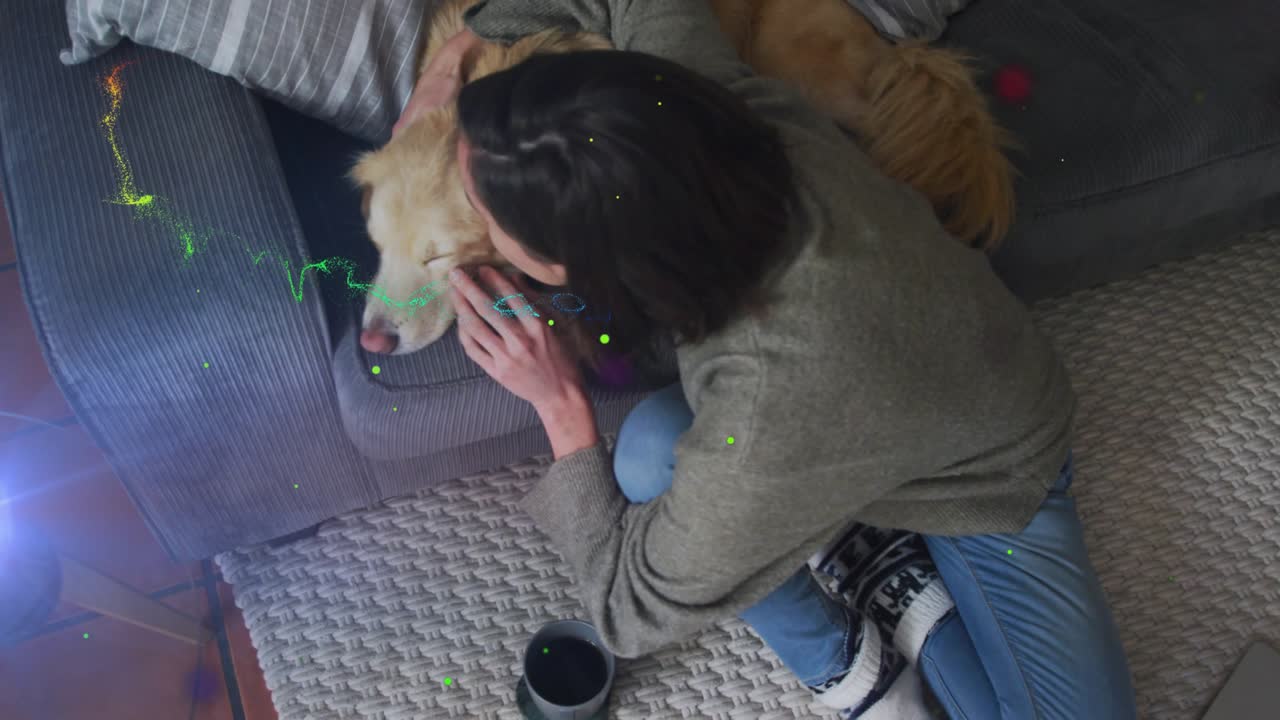 Kneeling woman touching, stroking dog's head to soothe dog amid spark trails highlighting pet care