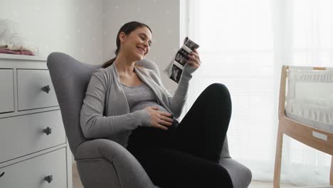 mid shot video of caucasian woman in advanced pregnancy browsing ultrasound scan in baby's room.