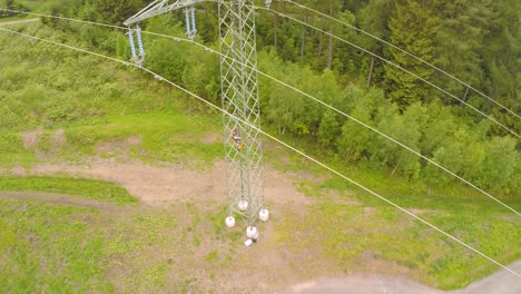 vista aérea de un trabajador bajando de una torre de transmisión en medio del bosque