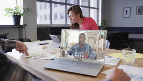 hombre de negocios caucásico en una llamada de video portátil con un colega afroamericano en la pantalla