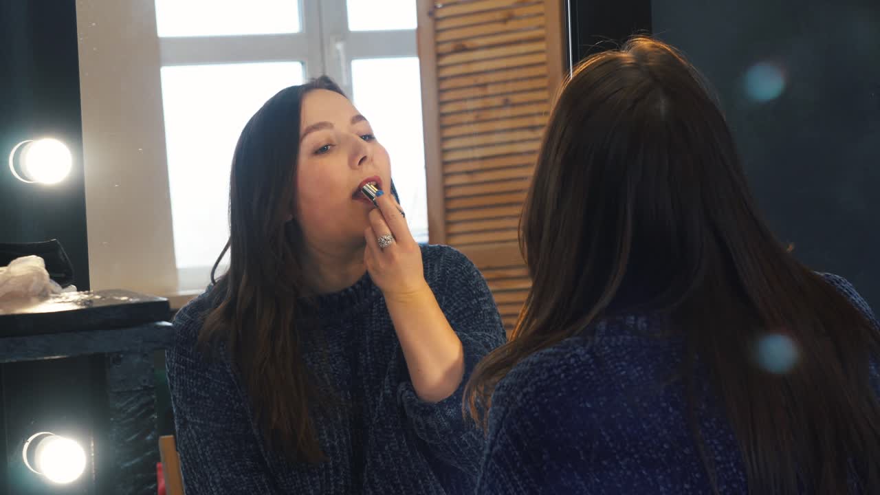 Woman Applying Lipstick in Front of a Mirror