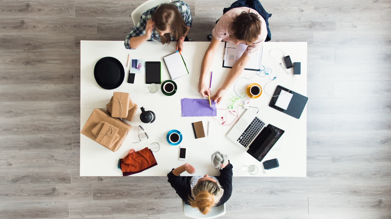 Timelapsed luftfoto af en blandet gruppe mennesker på et hipsterkontor i en lille startup-virksomhed, der planlægger et kreativt møde.