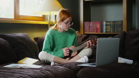 una adolescente aprendiendo ukulele en línea en casa