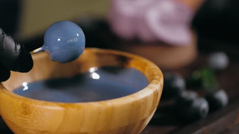 pastry chef is dips a candy in caramel for topping a blueberry cake, close-up