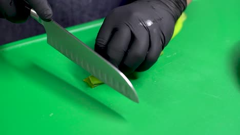 las manos del chef cortando cebolla verde en la tabla de cortar verde, de cerca