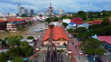 Toma-Aérea-épica-De-Un-Barco-De-Guerra-Histórico,-Río-Y-Edificios-Antiguos-En-Malaca,-Malasia,-Asia