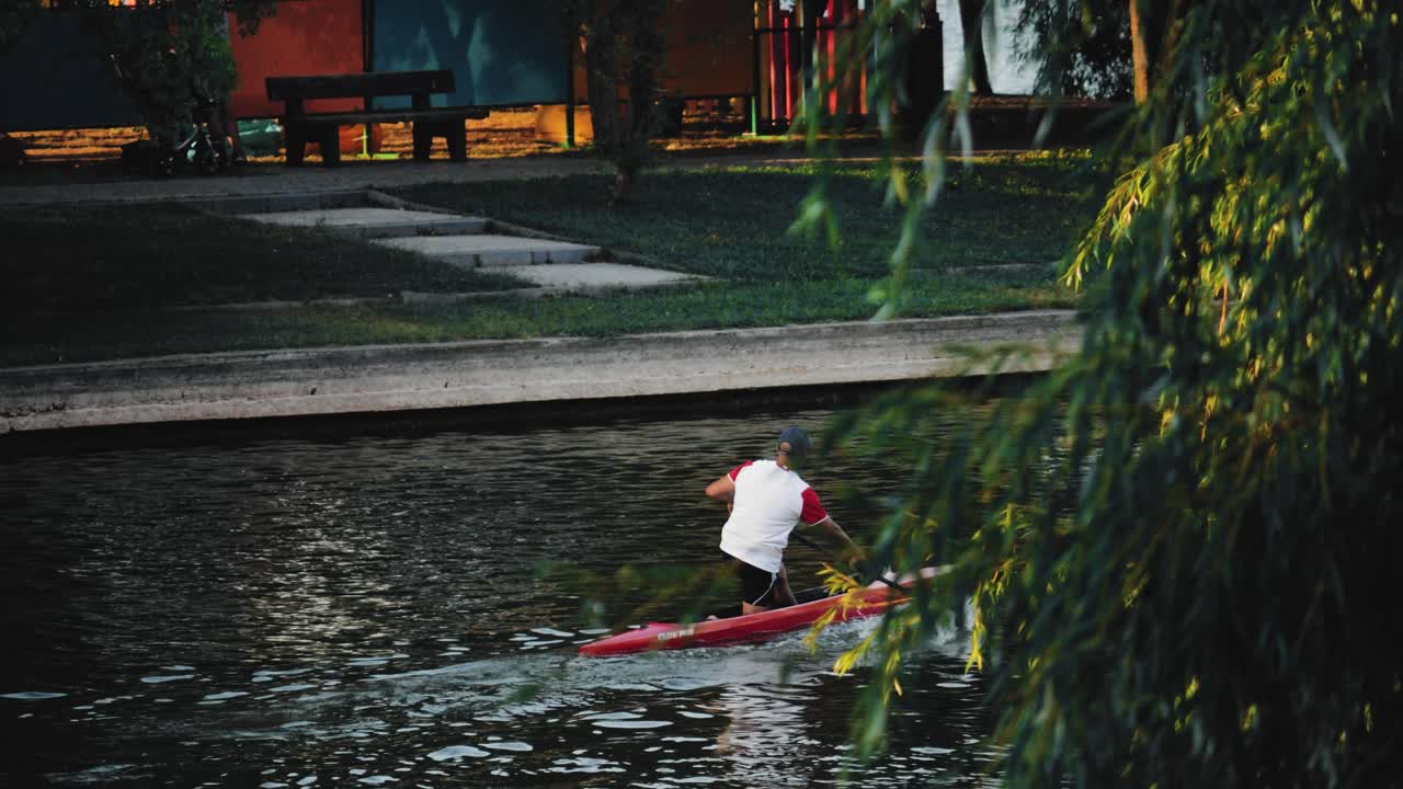 호수 뒤에서 카약을 타고 노를 젓는 남자를 보여주는 정적 샷