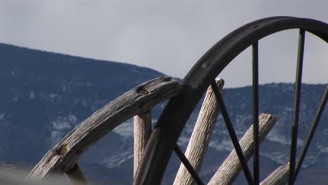 camera looks at mountains through the broken spokes of abandoned wagon wheels