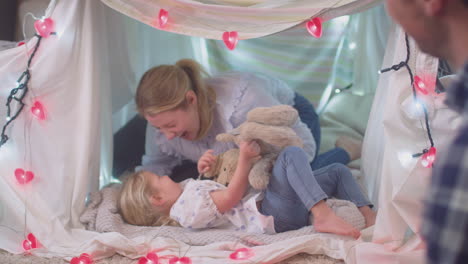 laughing parents with young daughter having fun in homemade camp in child's bedroom at home - shot on slow motion