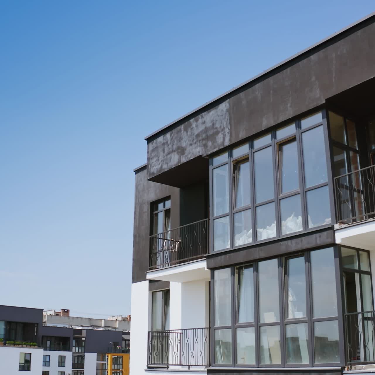 Modern multi-storey building. Large glazed balconies of the new high-rise building. Black and white apartment building in modern design in the city. Camera rising