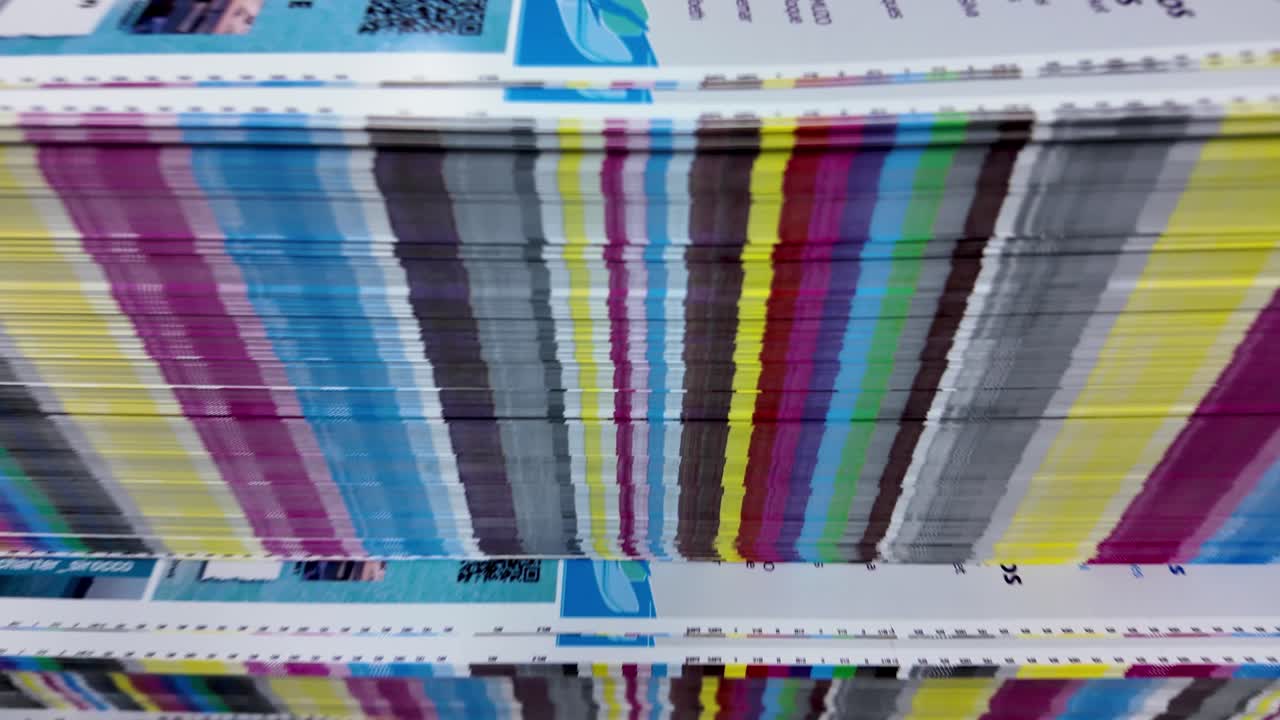 Stack of printed papers, showing colorful stripes of ink on the edges. Highlights layered texture of paper and colors, which appear as dense pattern of vertical lines, large volume of printed material
