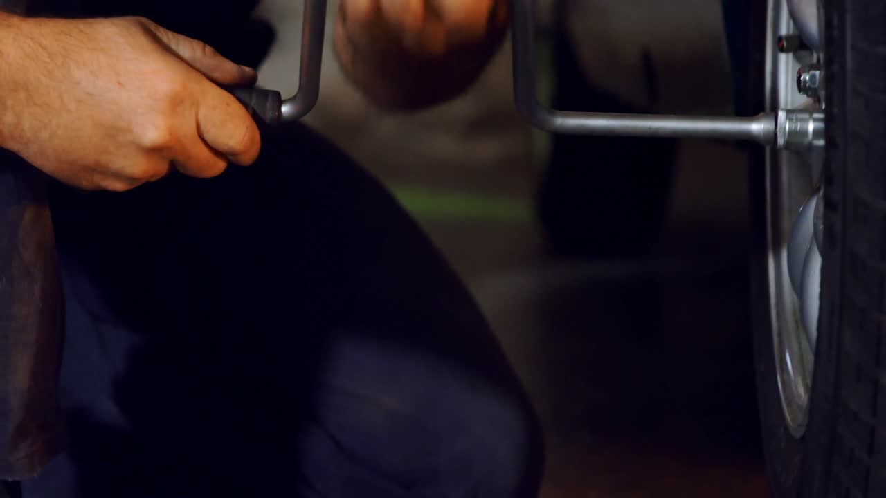 남성 기계가  ⁇  렌치와 함께 자동차 타이어를 수리 4k