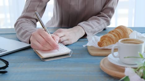 close up of young businesswoman making notes in notebook at home office. closeup woman hand writing in diary in slow motion.