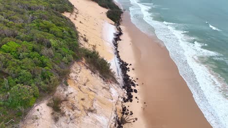 Aerial-of-people-walking-along-the-pristine-beach-and-surfers-enjoying-the-waves