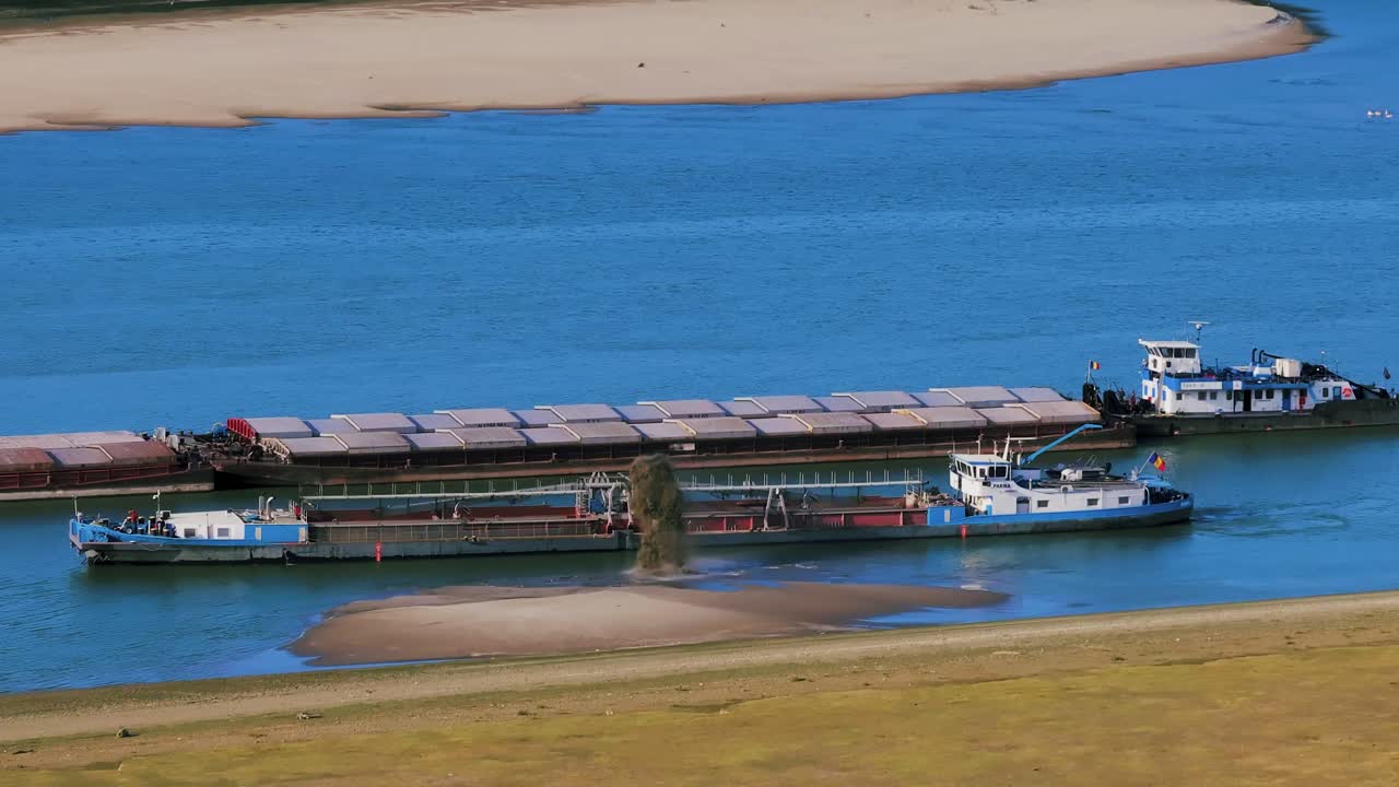 Aerial close up shot of a dredger unloading dredged sand on a big river, other ships passing by, sunny day