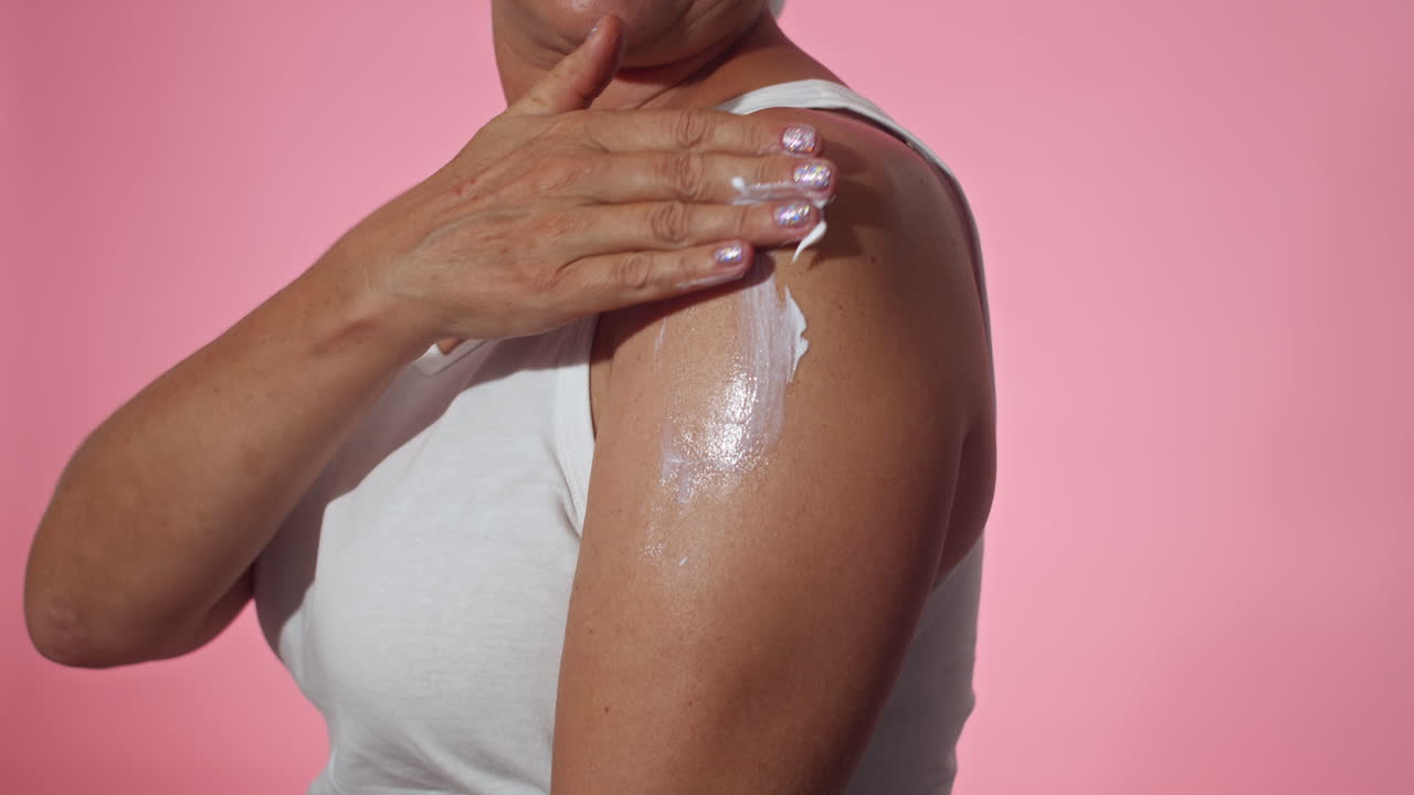 Mujer irreconocible aplicando crema solar o loción hidratante en el brazo