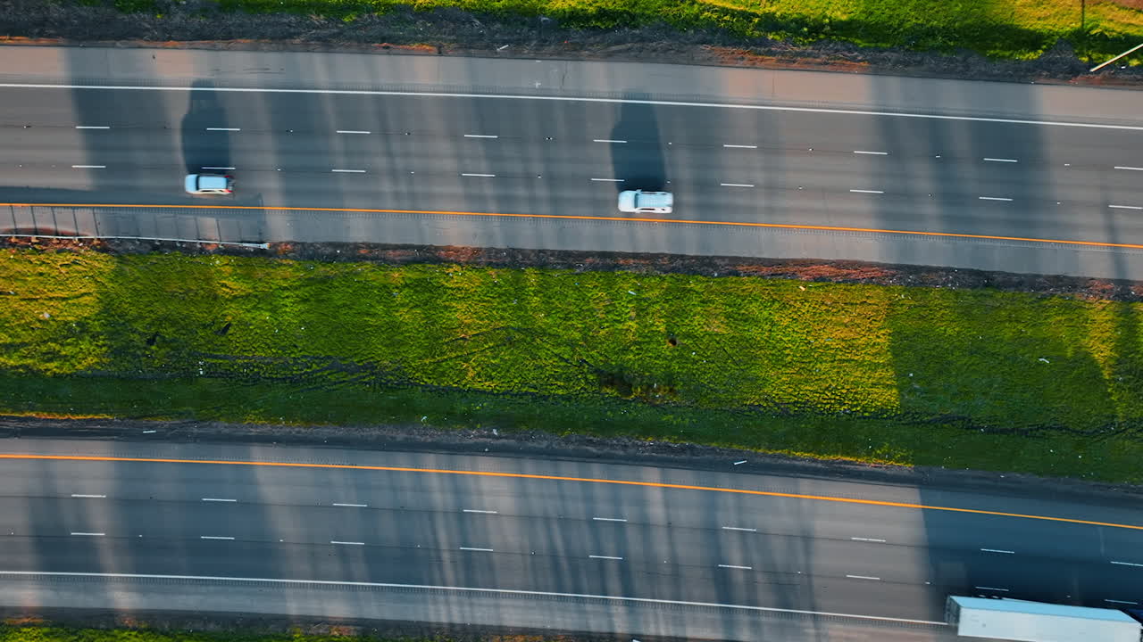 Lorries and cars drive by the highways to both sides. Top view on the roads at daytime.