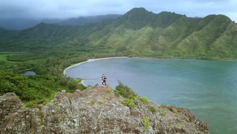 drone shot circling a pair of hikers standing on top of the cliffs on the crouching lion hike on oahu, hawaii