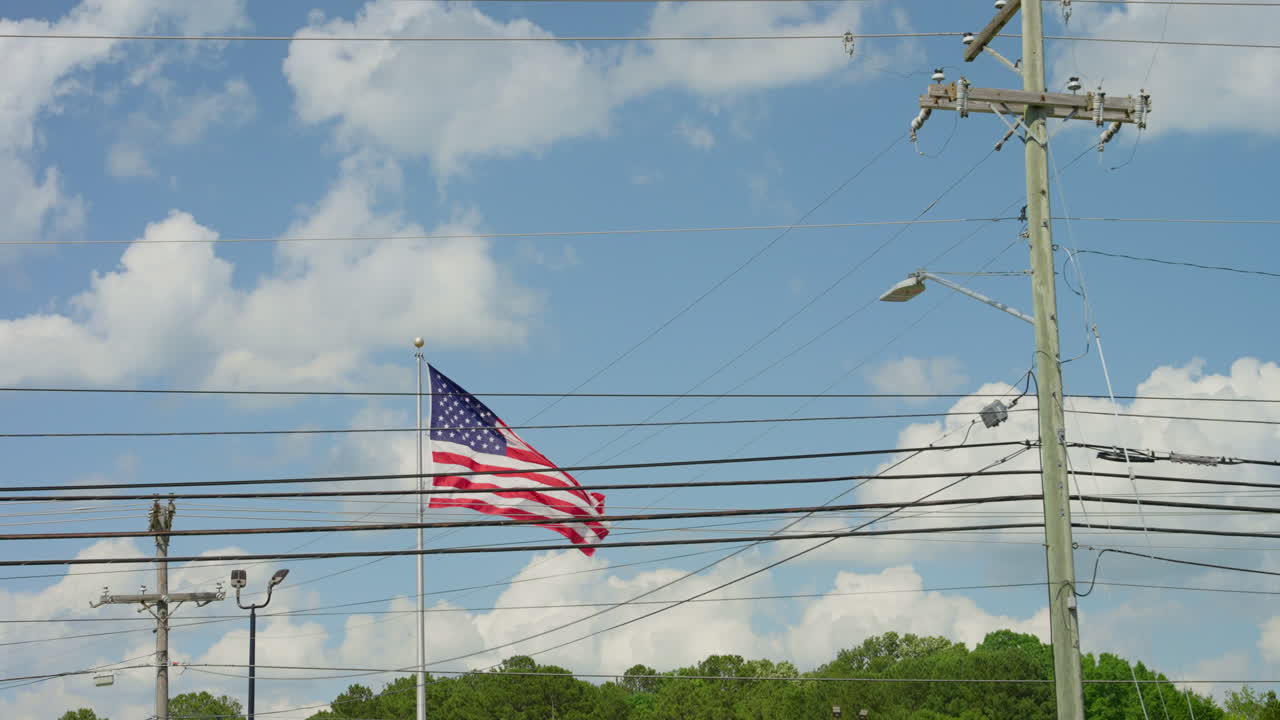 An American flag gracefully billows in the wind against a clear blue sky, symbolizing patriotism, freedom, and national pride. Stars and stripes ripple with movement. celebration of the United States.