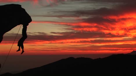 mediumshot of a rockclimber silhouetted by a fiery california settingsun