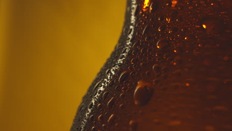 Macro-Shot-Of-Condensation-Droplets-On-Revolving-Bottle-Of-Cold-Beer-Or-Soft-Drinks-Against-Yellow-Background-1