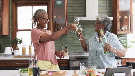 Felices-Amigas-Afroamericanas-Mayores-Brindando-Con-Vino-Mientras-Cocinan,-Cámara-Lenta