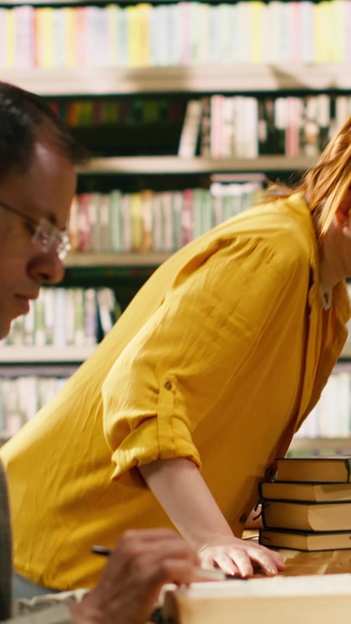 Vertical Video University students focus on books and notes at a long library table