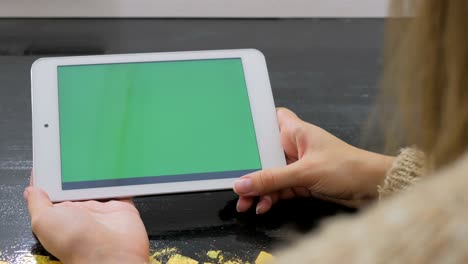 woman looking at tablet computer with green screen