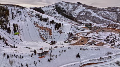 park city utah aerial v23 snowy mountainscape view drone flyover olympic park slopes, uphill tilt down birds eye view capturing the mountain top complex - shot with mavic 3 cine - february 2022