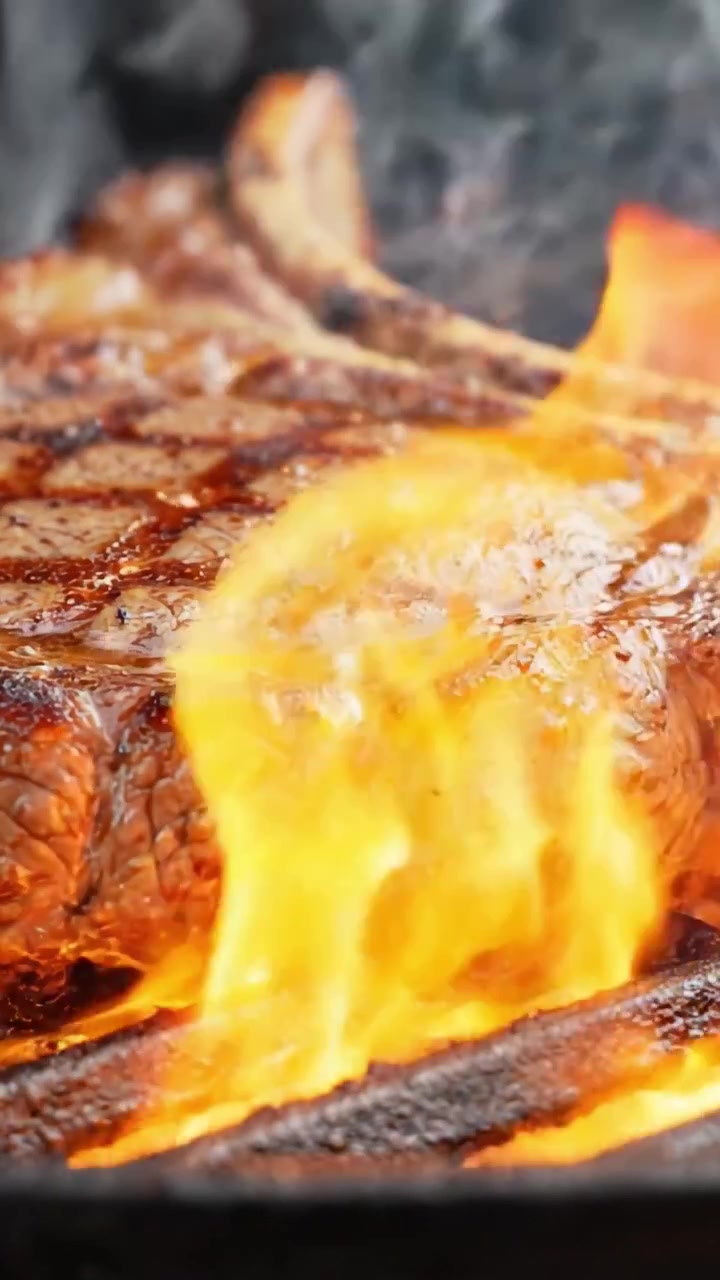 Sissende perfectie: Een close-up van een sappige biefstuk die boven vlammen grilt, waarbij de perfecte korst en smaakontwikkeling worden vastgelegd in een overheerlijke BBQ-ervaring.