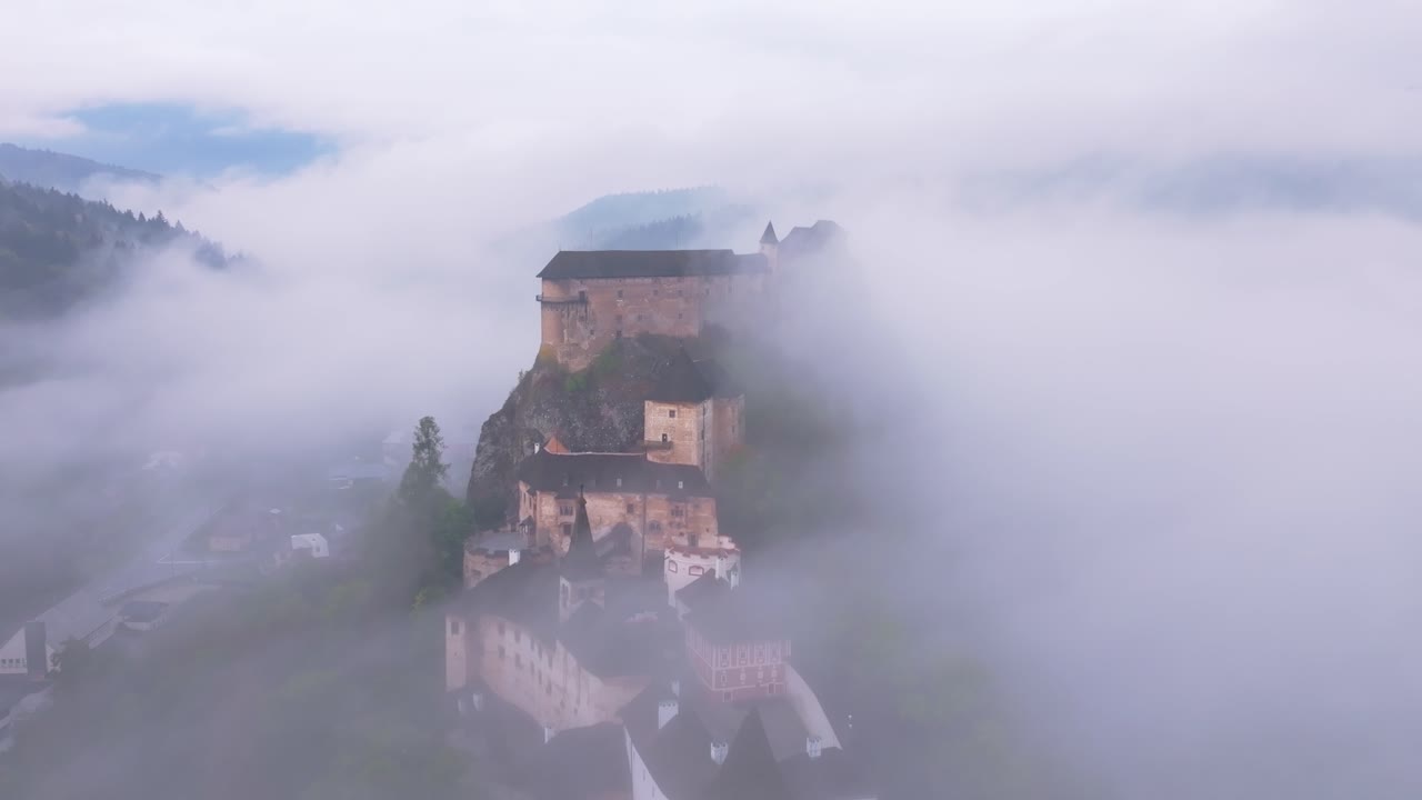 Aerial glimpse of Orava Castle floating above the clouds at dawn