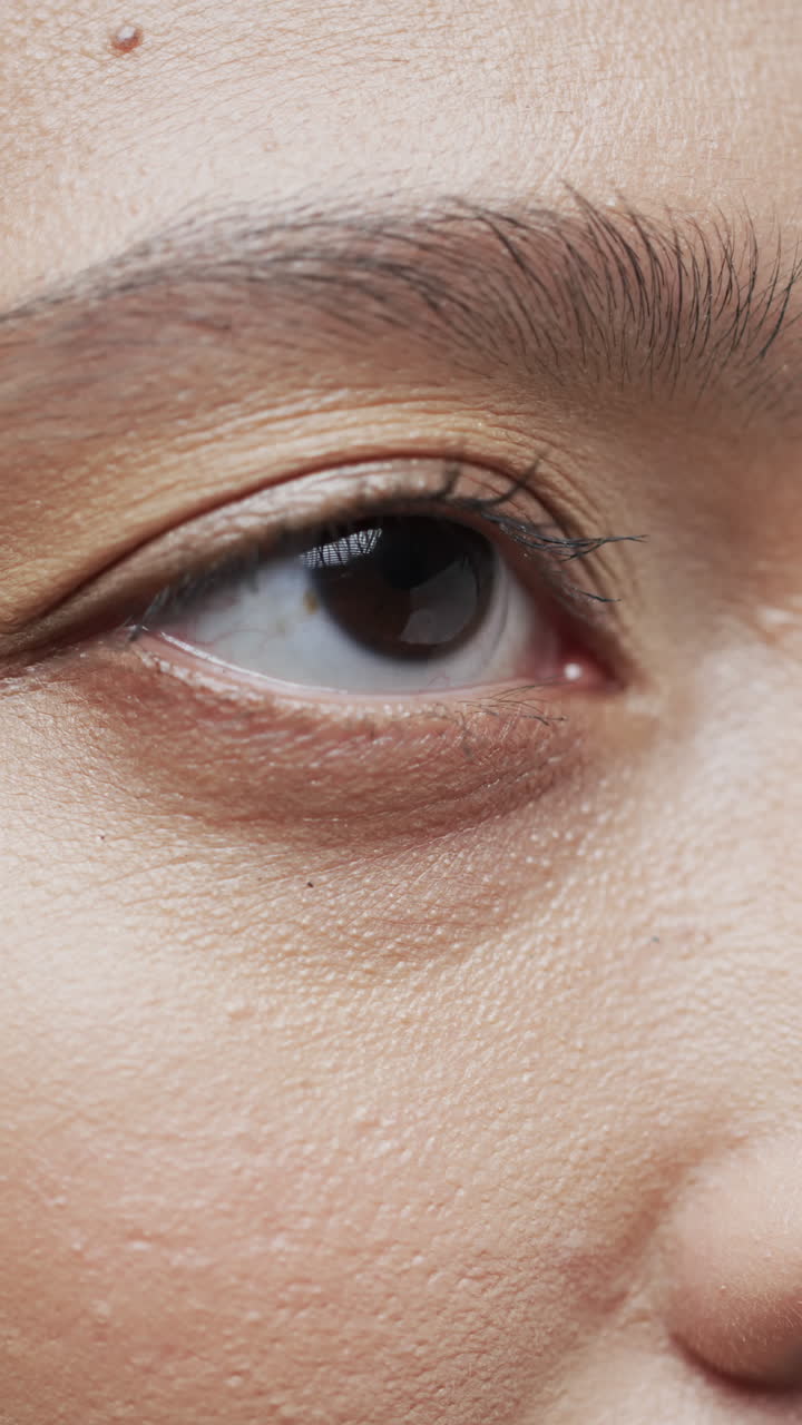 Vertical video of eye of asian woman with dark hair, slow motion