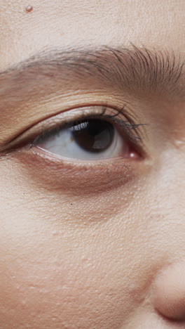 vertical video of eye of asian woman with dark hair, slow motion