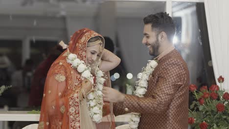 una pareja india intercambiando guirnaldas blancas durante la ceremonia de bodas - de cerca