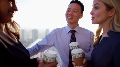 multi ethnic business managers drinking coffee on rooftop