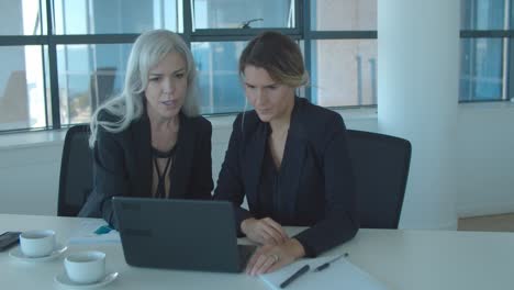 focused female colleagues using laptop together